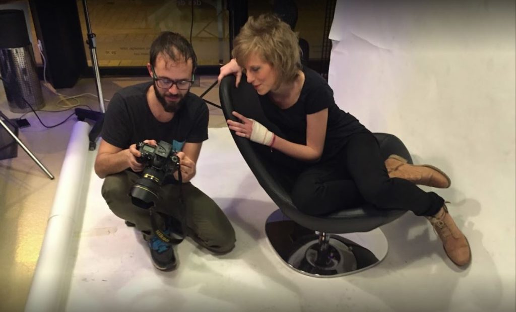 Fotògraf mostra la càmera a un model assegut.